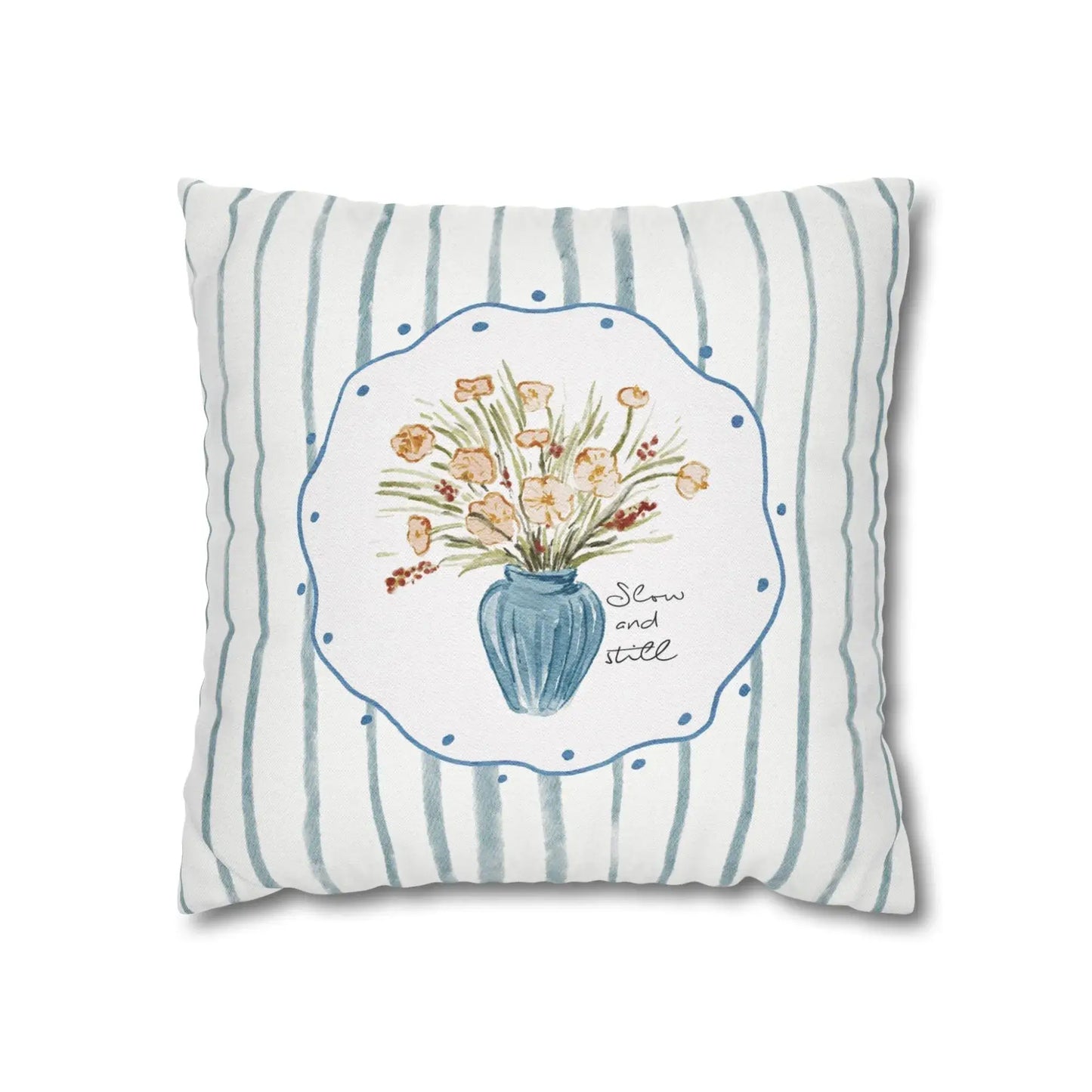 Blue and white striped pillow with watercolor-style flower bouquet in a vase and the phrase "Slow and still."