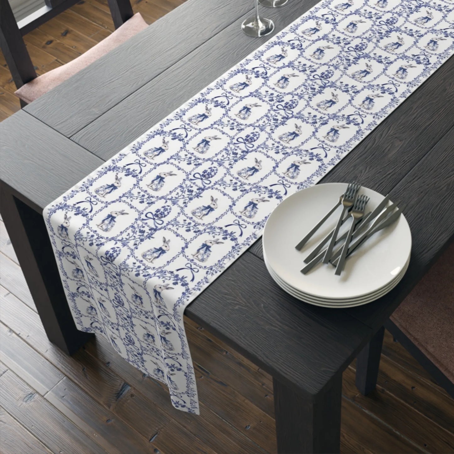 Blue and white table runner with a watercolor rabbit and Chinoiserie floral pattern on a dark wood dining table with plates and forks.