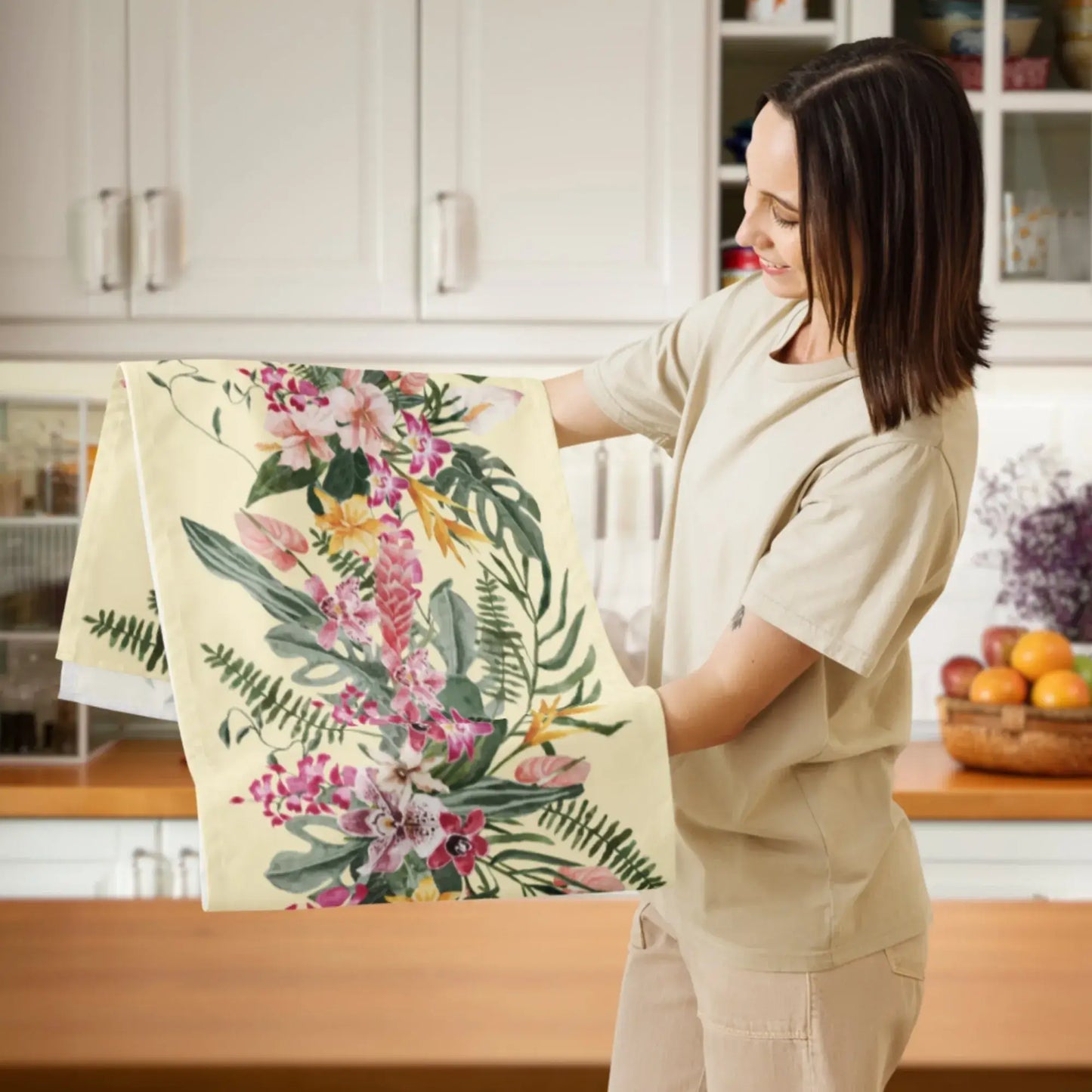 Floral Tropical TABLE RUNNER in light yellow with orchid design held by a woman in a kitchen setting.