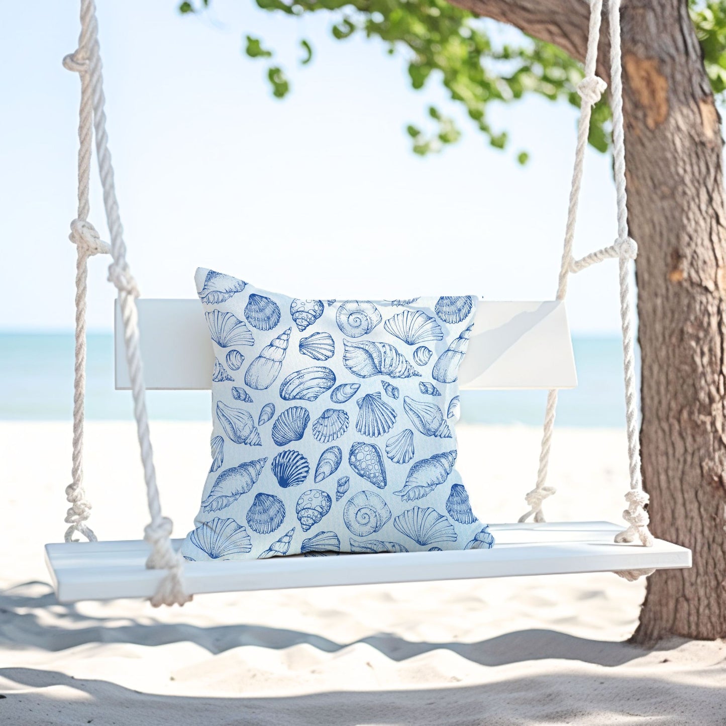 Seashell pillow cover on white swing at the beach — modern coastal summer decor