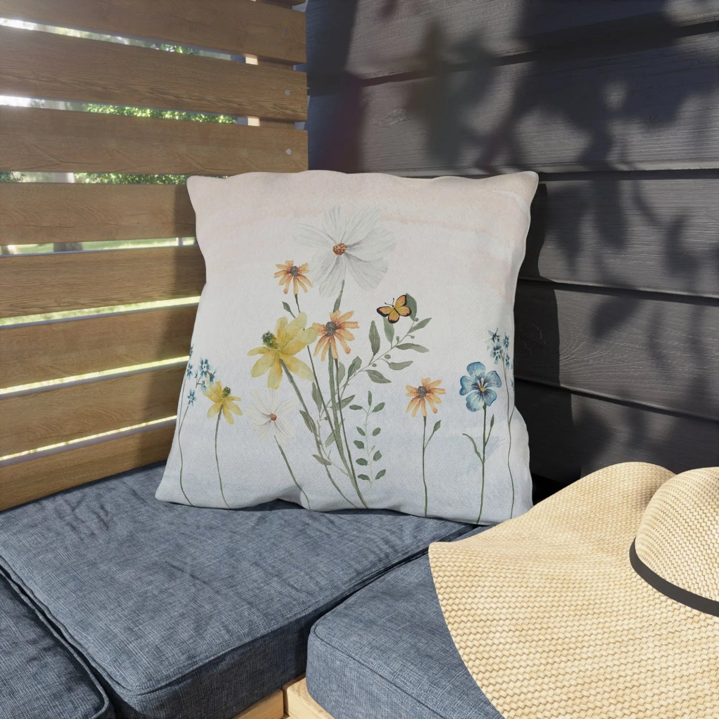 Nature-inspired outdoor pillow with wildflower and butterfly print on a patio bench, perfect for seasonal decor and modern farmhouse style.