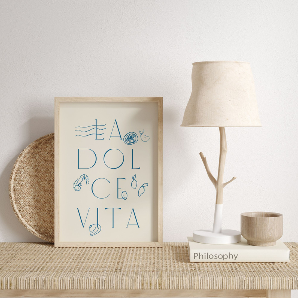 Printable La Dolce Vita poster with blue sea-inspired lettering styled on a rattan console with neutral decor and soft lighting