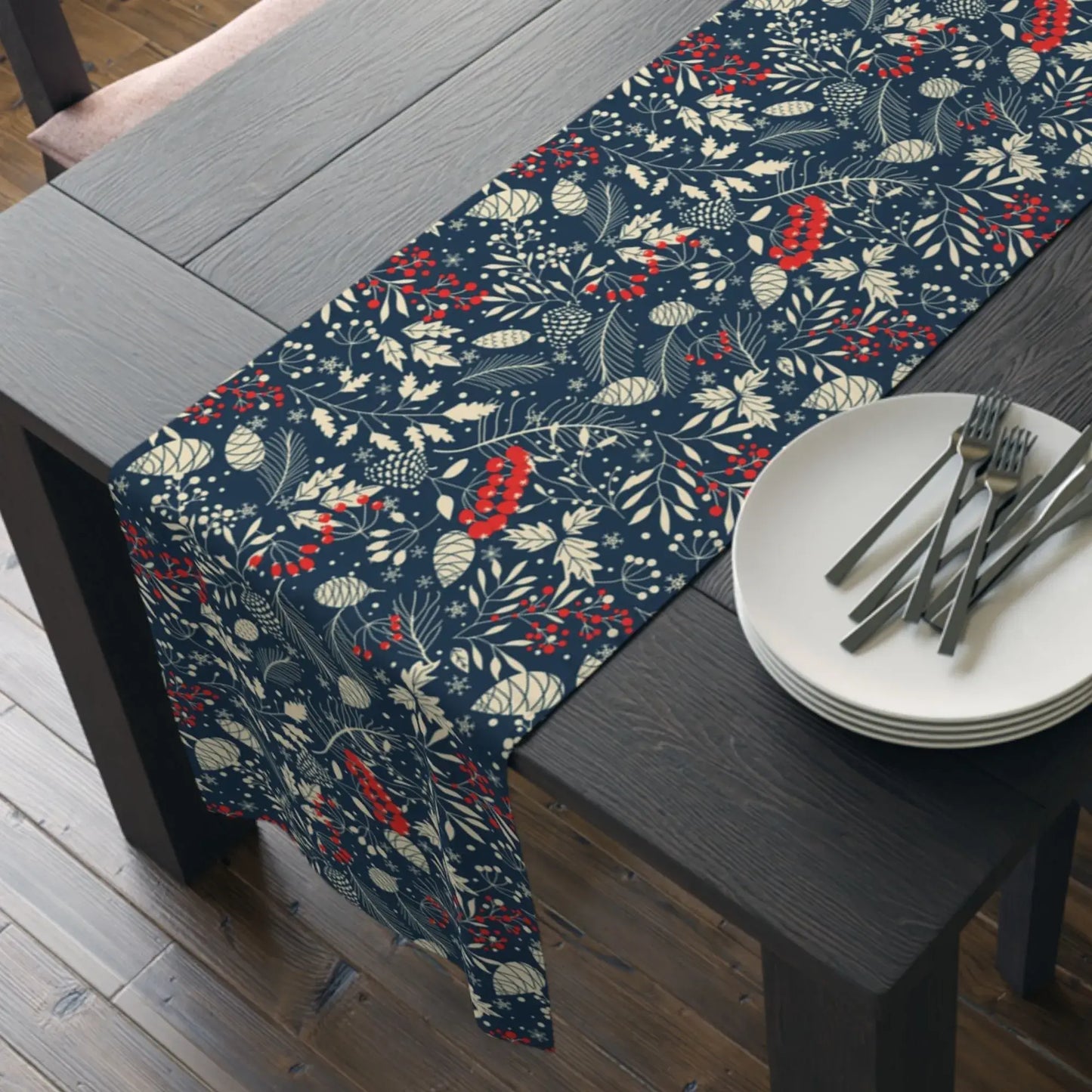 Blue Winter Botanical Christmas Table Runner displayed on a wooden dining table with plates and cutlery.