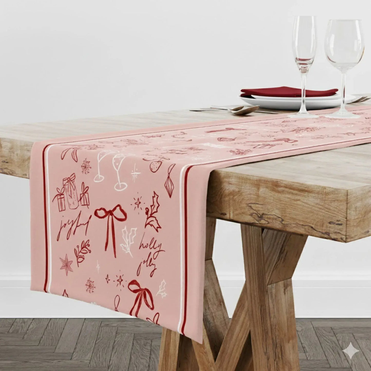 Blush Pink Christmas Table Runner with red line art of bows and holiday designs on a wooden table.