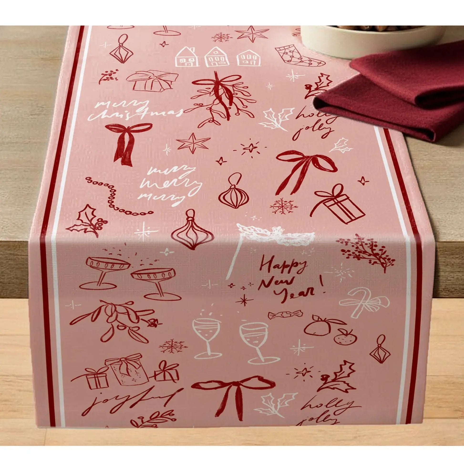 Blush Pink Christmas Table Runner with red line art featuring bows, holly, and holiday wishes on a smooth table surface.