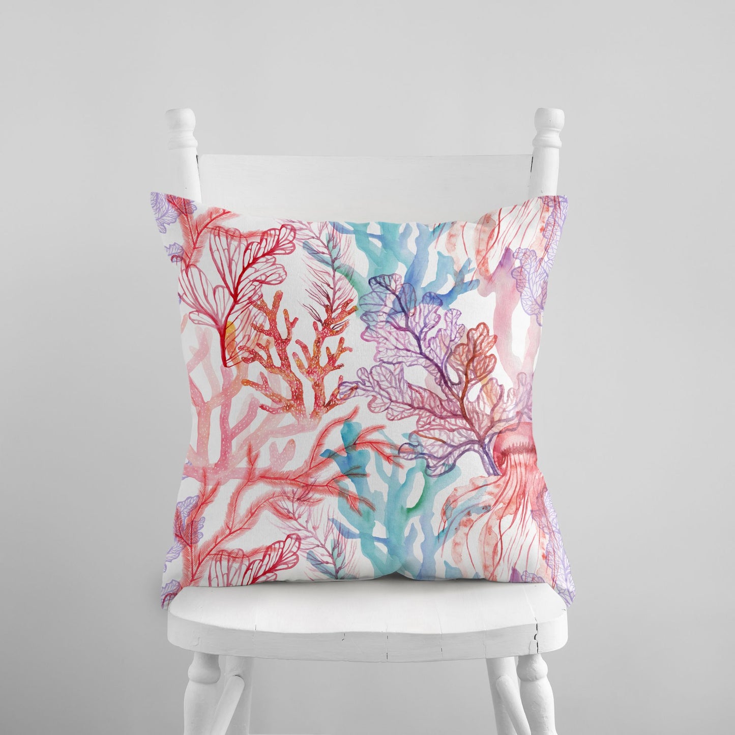 Coral reef throw pillow on white chair. Ocean-themed decorative pillow with colorful coral design.