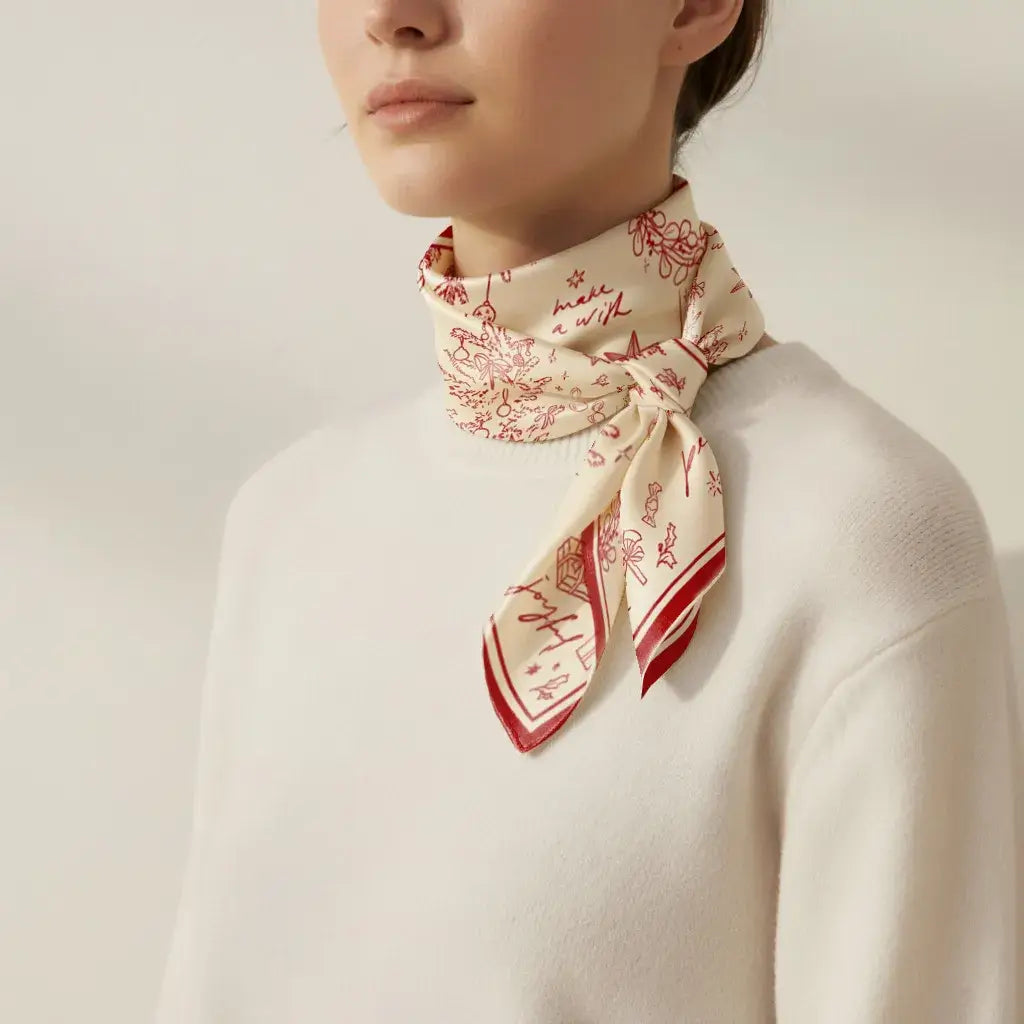 Model wearing Christmas Silk Scarf “Make a Wish” in red and ivory hand-drawn festive design tied around neck.