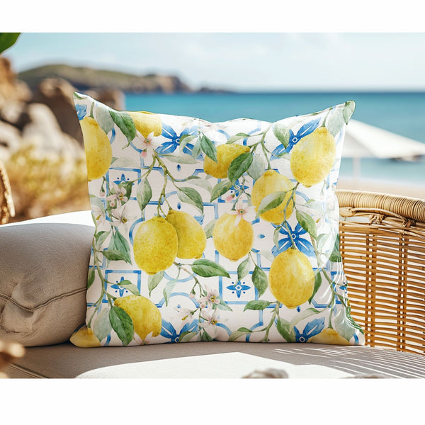 Watercolor Italy Lemon Outdoor Pillow sitting on rattan chair nearby the beach