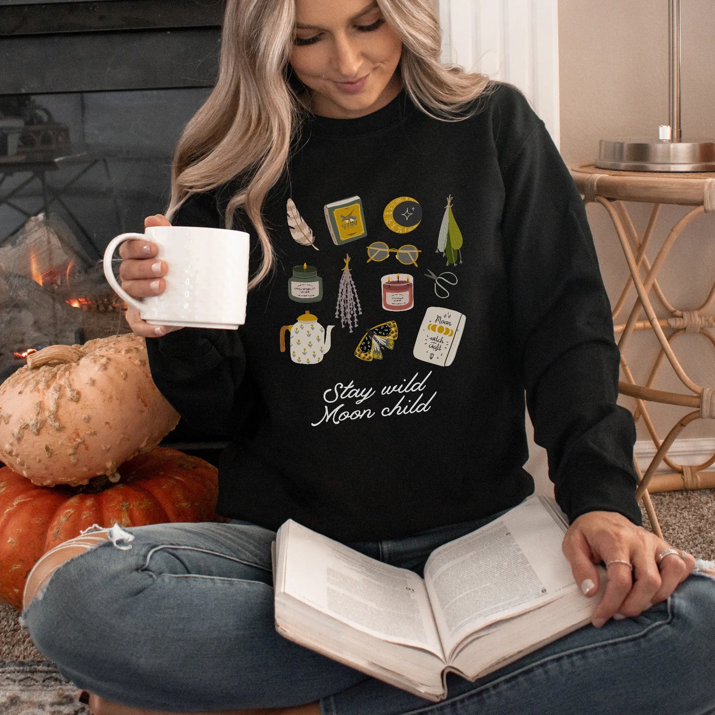 cottage witch in black sweatshirt from Blue Water Songs reading a book