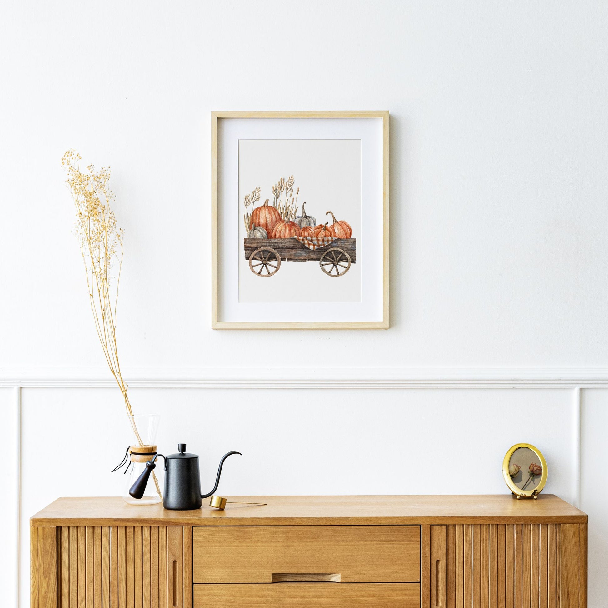 Pumpkin cart painting from Blue Water Songs hanging above wood cabinet 