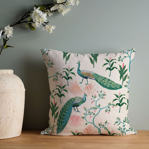 Chinoiserie Beige Peacocks Chinoiserie throw PILLOW from Blue Water Songs leaning on green wall next to white cherry blossoms vase