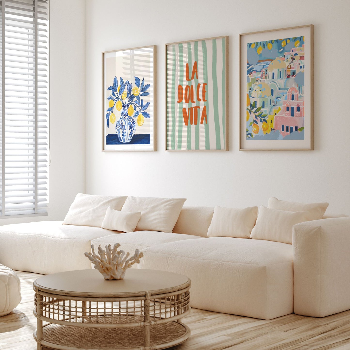 Framed summer art prints above white sofa featuring lemons, La Dolce Vita text, and pastel coastal village scene