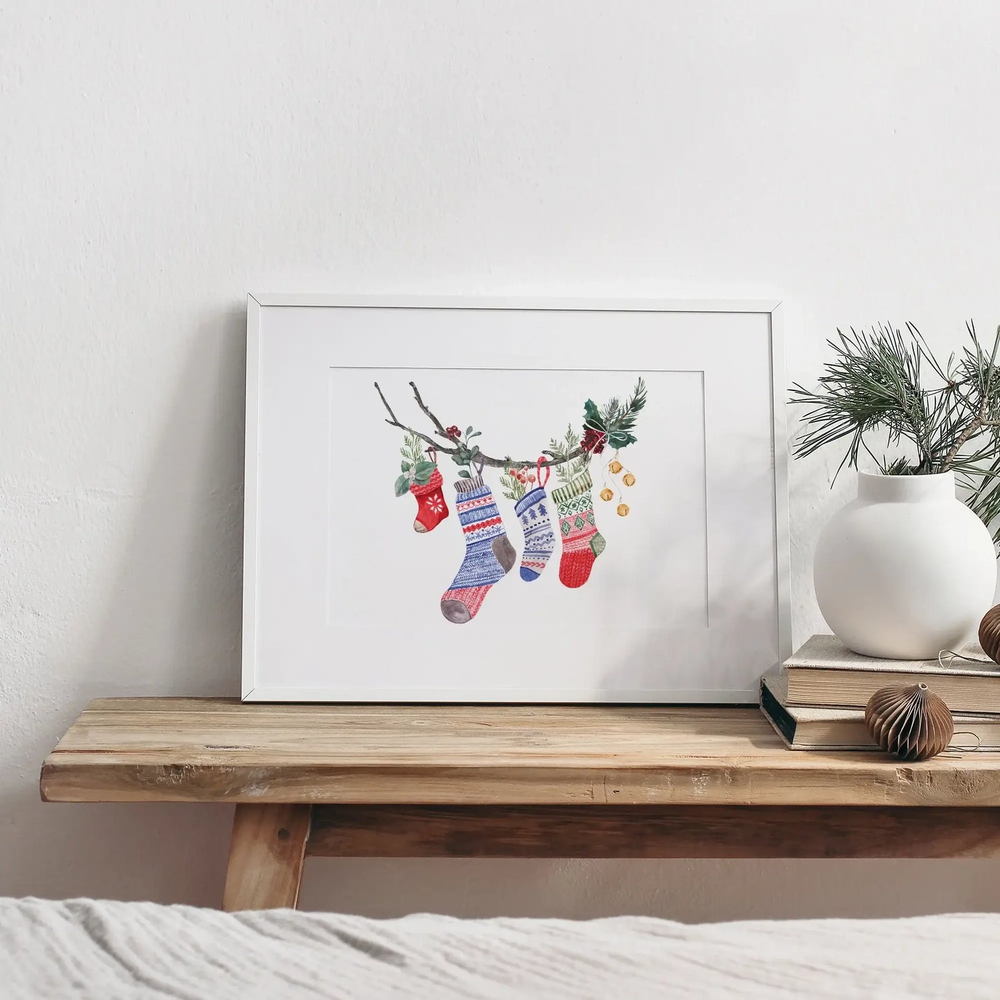 Watercolor Christmas Stocking Art Print displayed in a modern frame on a wooden table with holiday decor.