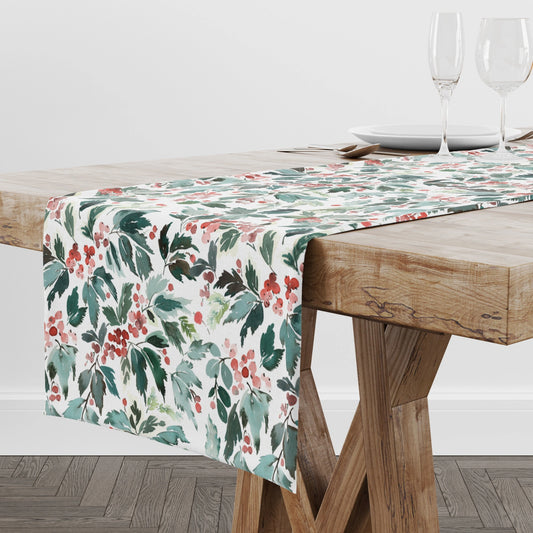 Watercolor Christmas Table Runner featuring red holly and green leaves on a wooden dining table.
