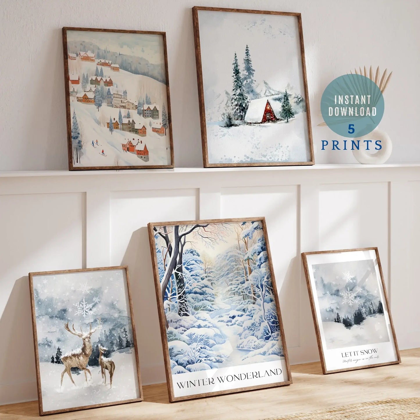 Winter Wonderland Prints Set of 5 displayed in frames, showcasing snowy landscapes and festive cottages.