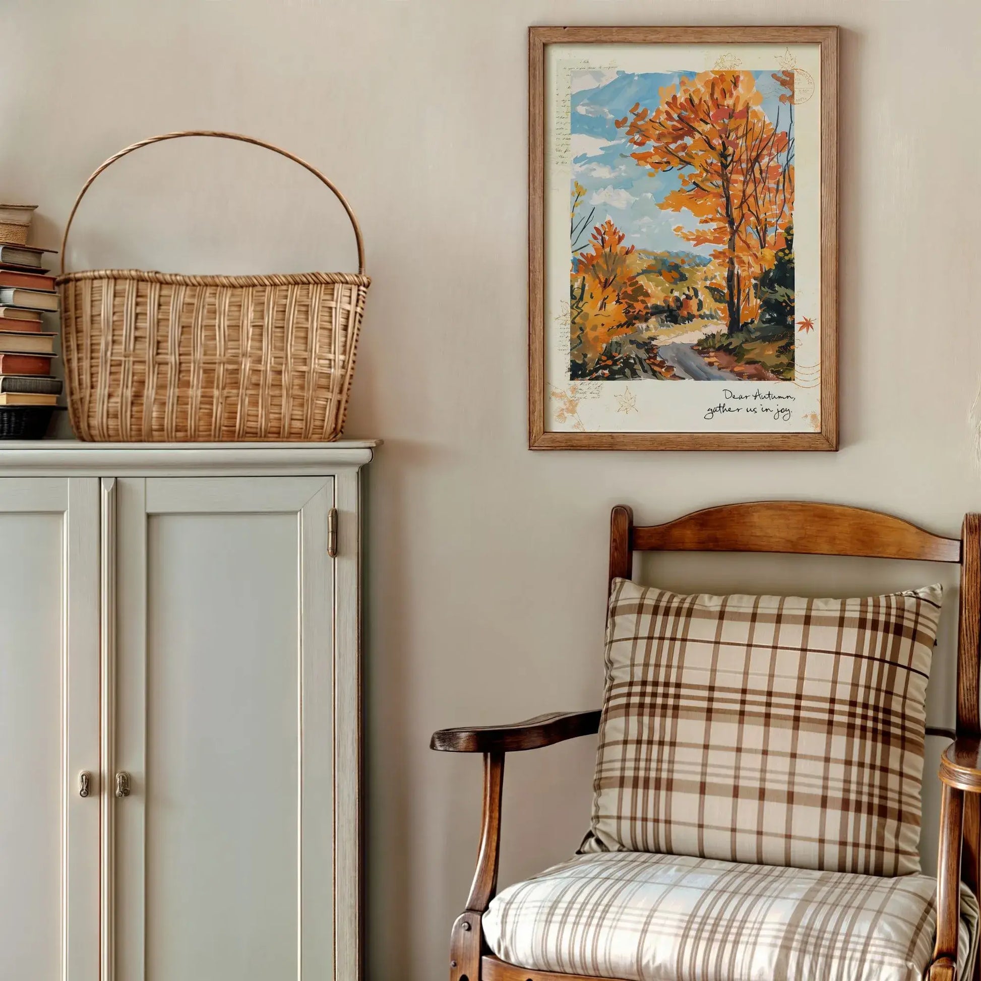 Framed autumnal wall art “Autumn Road” with golden trees, styled above a cabinet and chair with plaid cushion for cozy seasonal decor