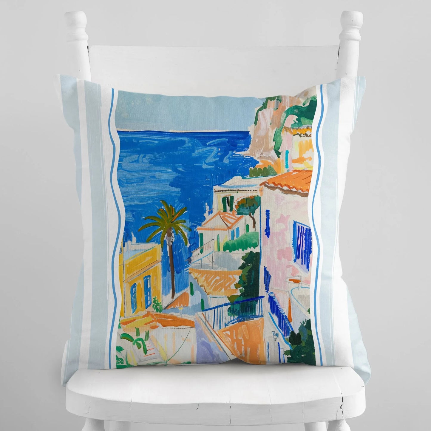 Mediterranean coastal view pillow cover with painted seaside houses and palm trees on a white chair