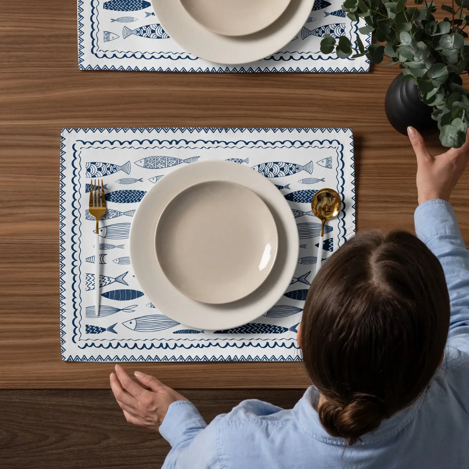 Blue Fish Cotton Placemats on a wooden table set with plates and utensils, featuring nautical fish designs.