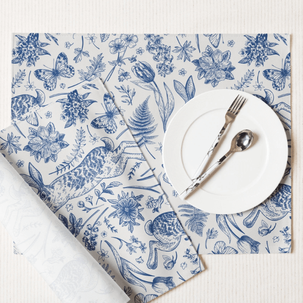 Blue Toile Bunny Placemats with detailed illustrations and a white plate and cutlery on top.