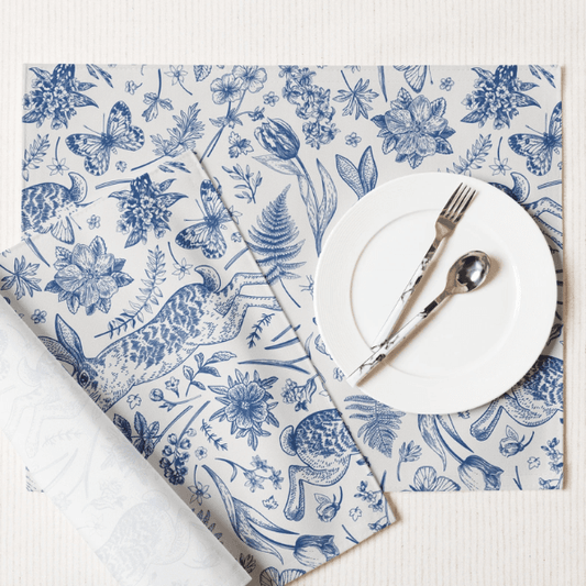 Blue Toile Bunny Placemats with detailed illustrations and a white plate and cutlery on top.