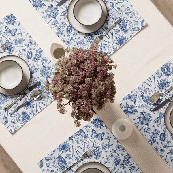Blue Toile Bunny Placemats arranged on a dining table with plates and a floral centerpiece.
