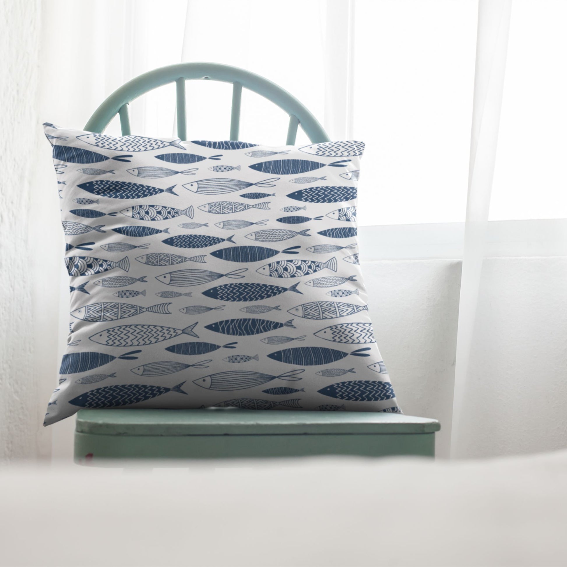 Blue fish throw pillow on green chair next to window