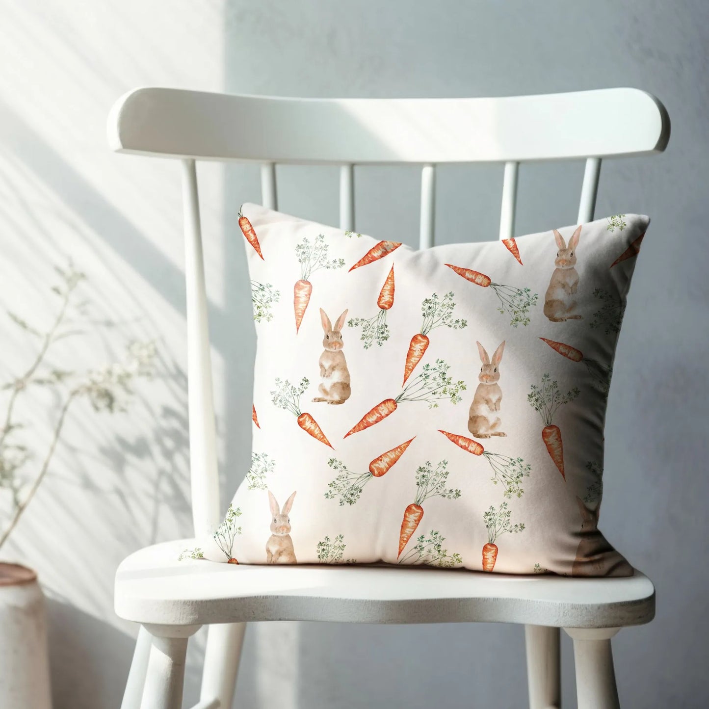 Watercolor bunny and carrot pillow sitting on a white chair, showcasing spring and nature-inspired home decor.