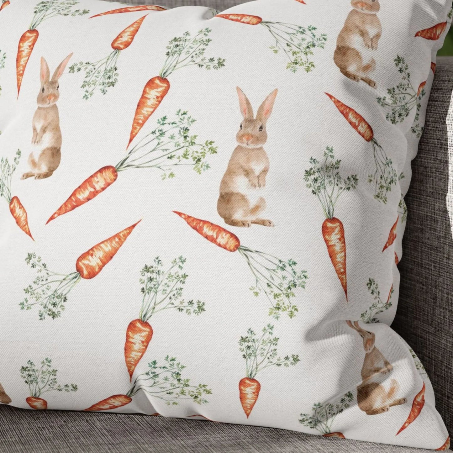 Close-up of a white pillow featuring a watercolor pattern of cute bunnies and bright orange carrots.