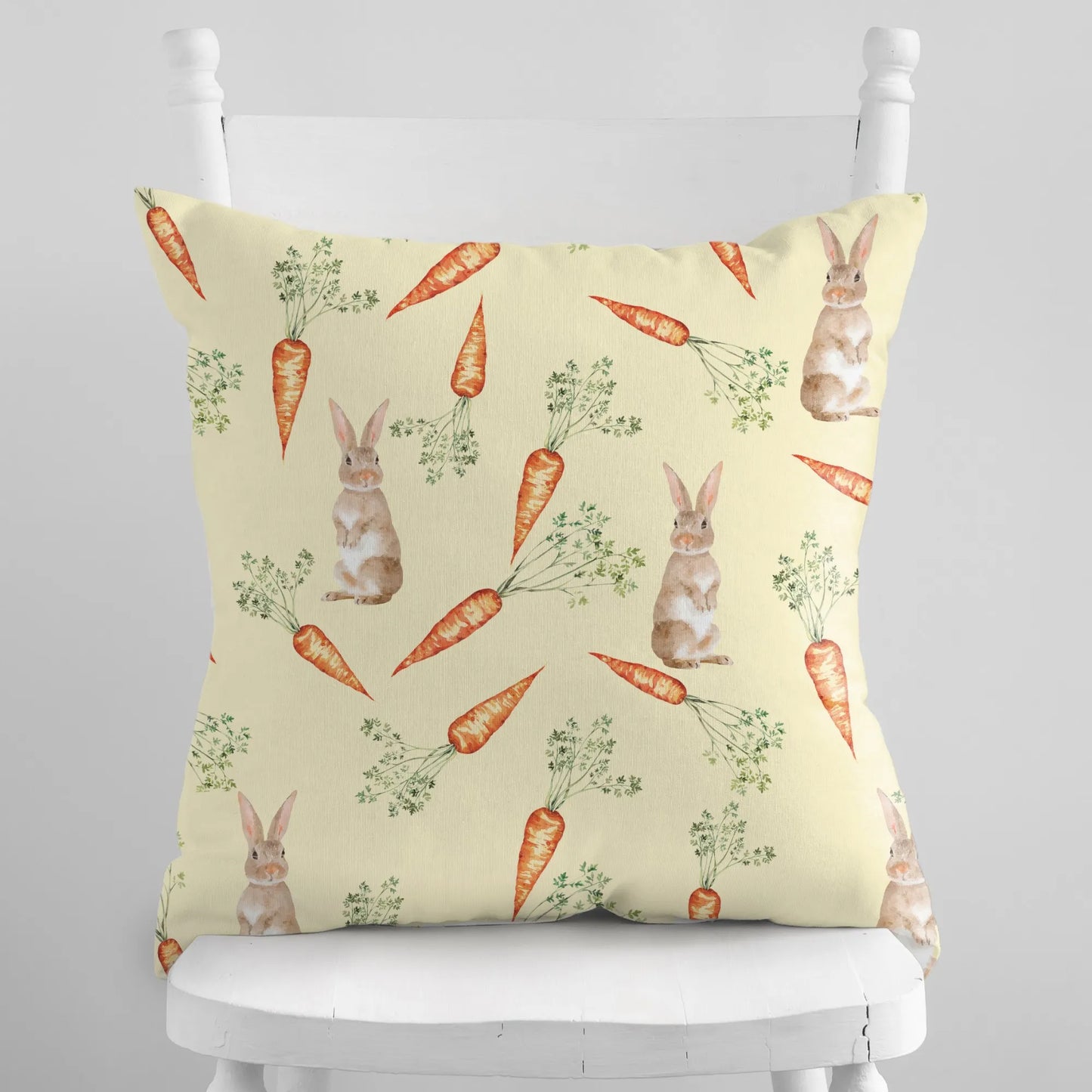 Soft yellow throw pillow featuring a watercolor bunny and carrot pattern, ideal for gentle spring or Easter decor.