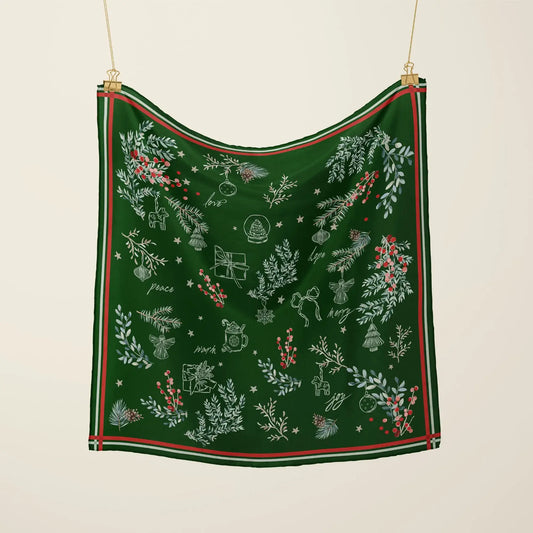 Christmas botanical silk scarf featuring pine branches, red berries, and festive motifs on a green background.