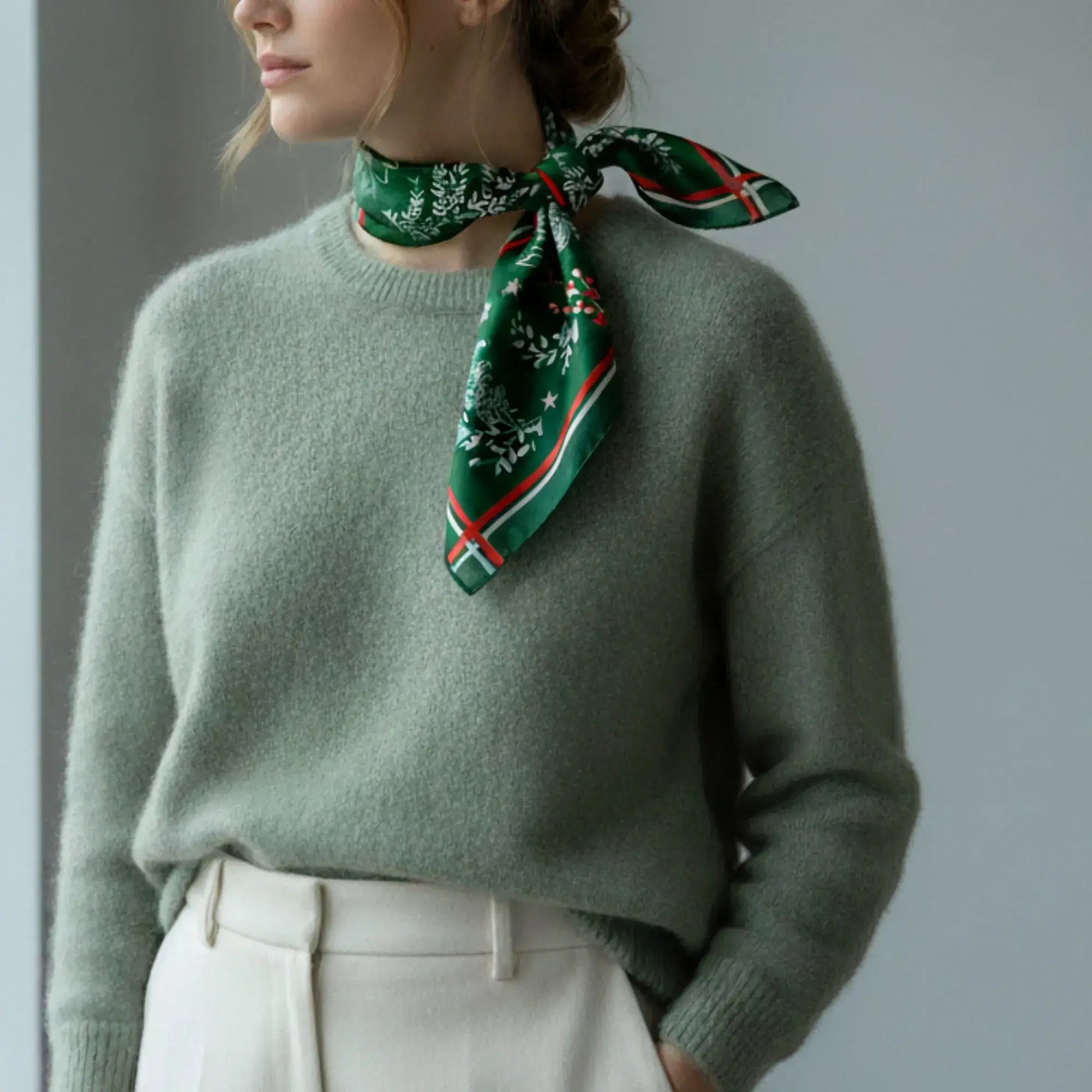 Christmas botanical silk scarf styled with a green pastel sweater, featuring a pine and red berry print.