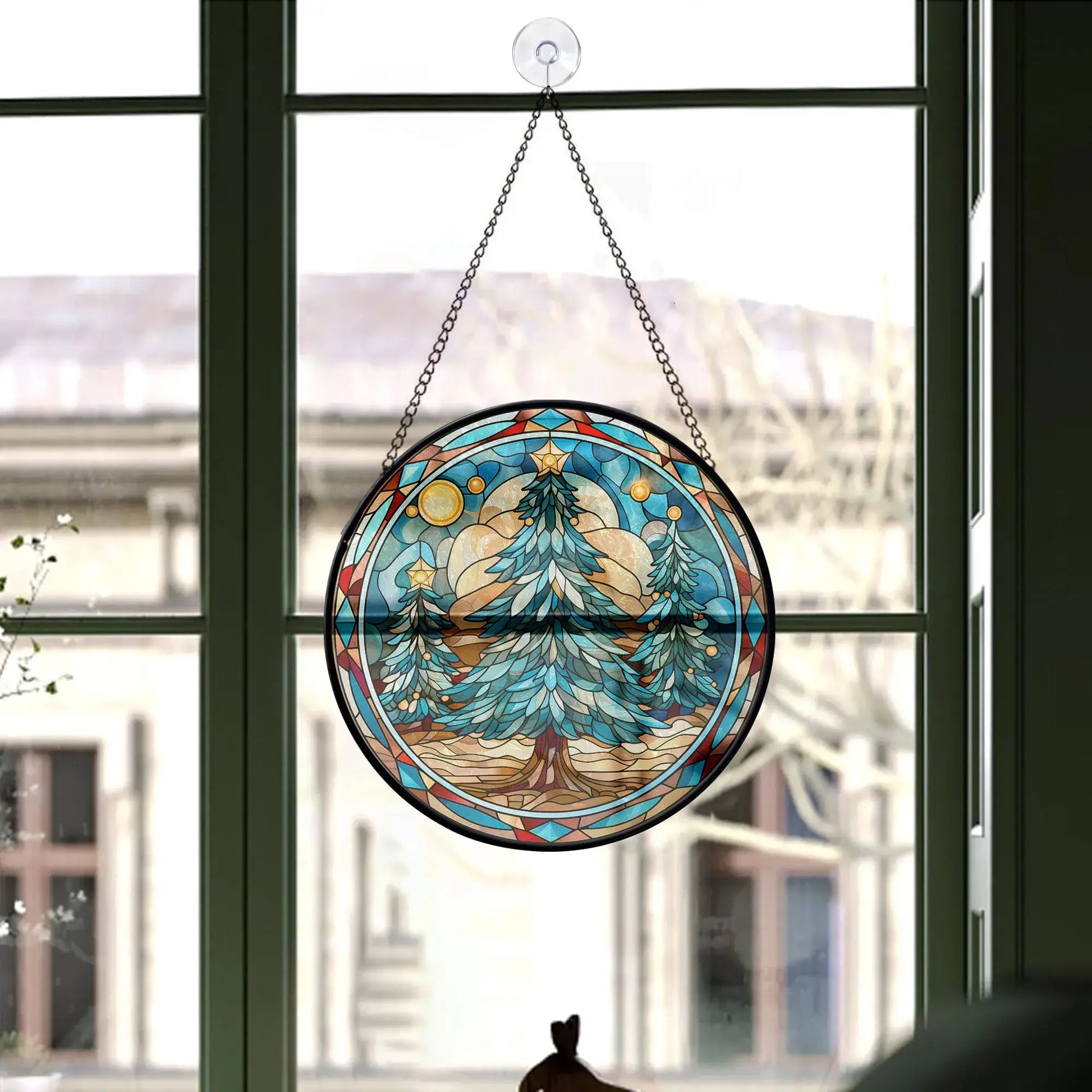 Christmas tree stained glass ornament hanging in a window showcasing blue tones and festive design.