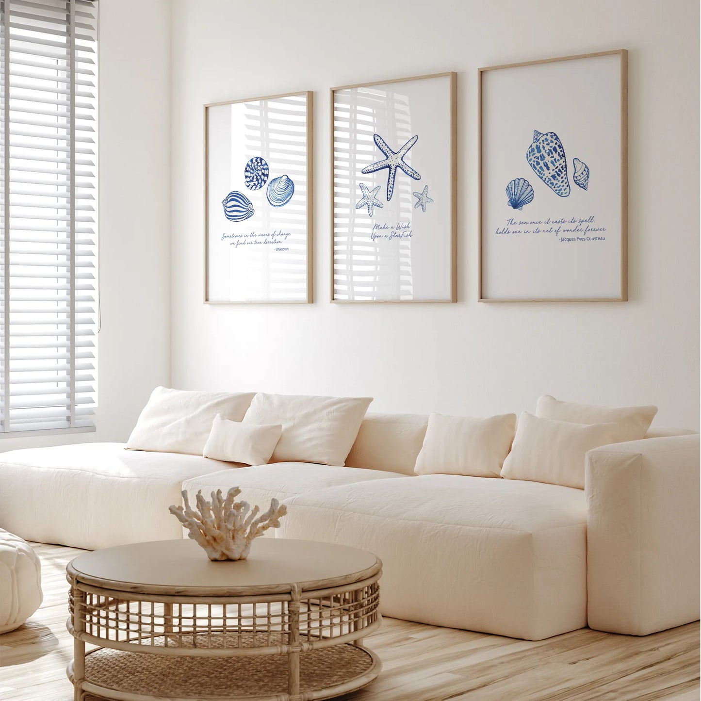 Coastal prints featuring blue seashell illustrations in a bright living room setting with a white couch and coffee table.