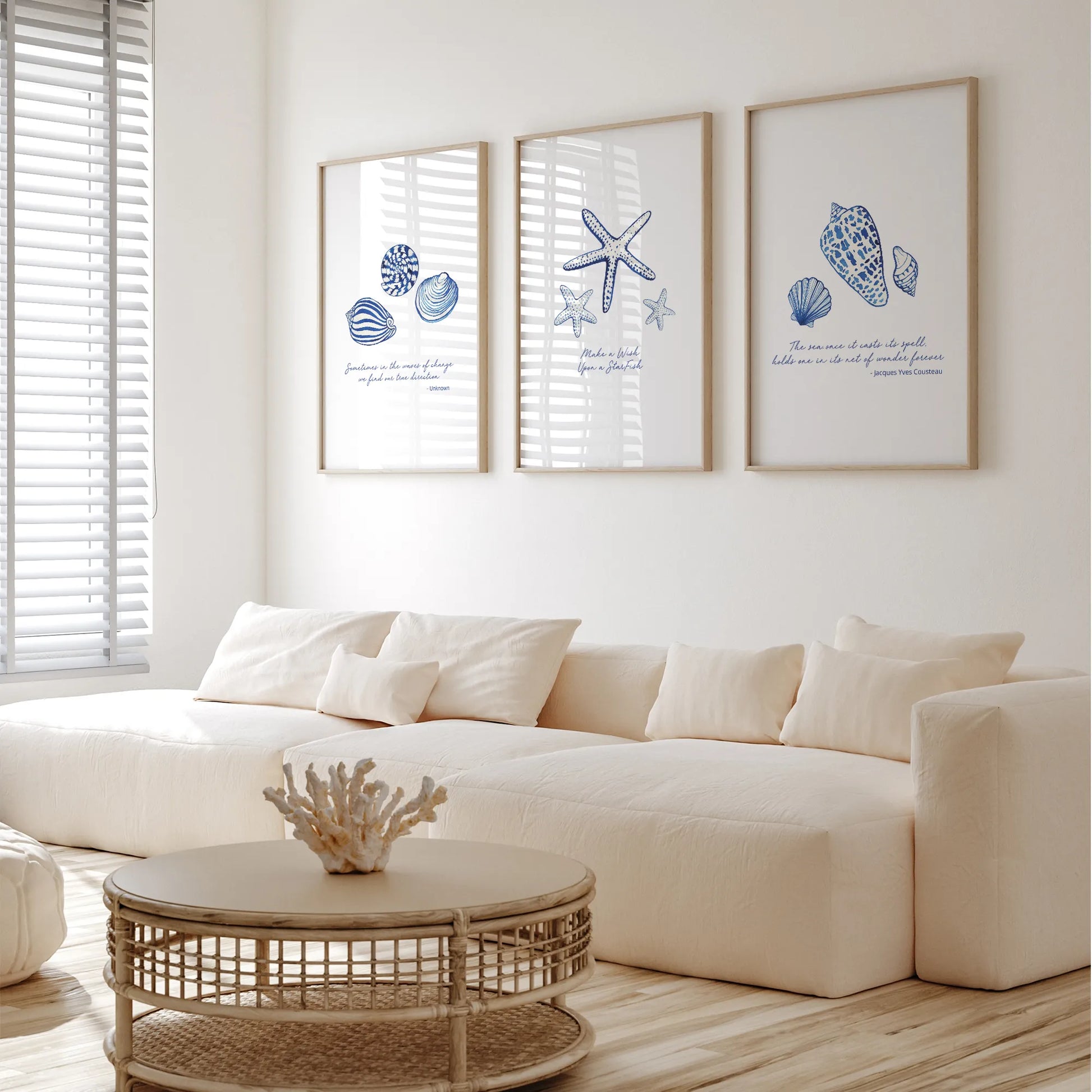 Coastal prints featuring blue seashell illustrations in a bright living room setting with a white couch and coffee table.