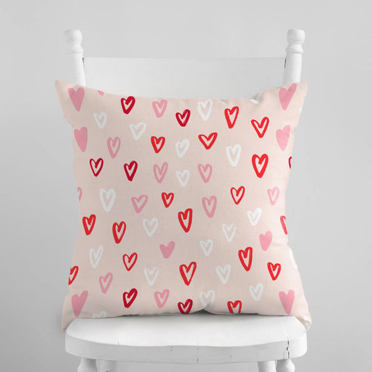 Cute hand-drawn hearts valentine pillow on a white chair, colorful heart patterns to enhance seasonal decor.