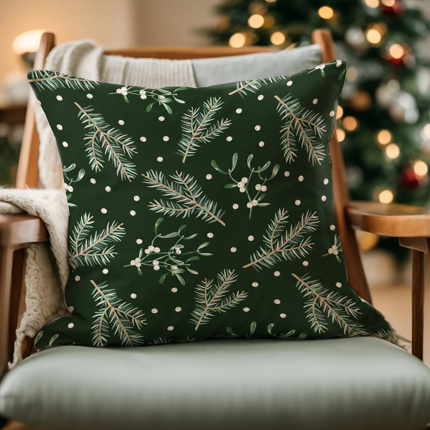 Dark green mistletoe Christmas pillow on chair with holiday lights – cozy botanical winter decor with pine and berries