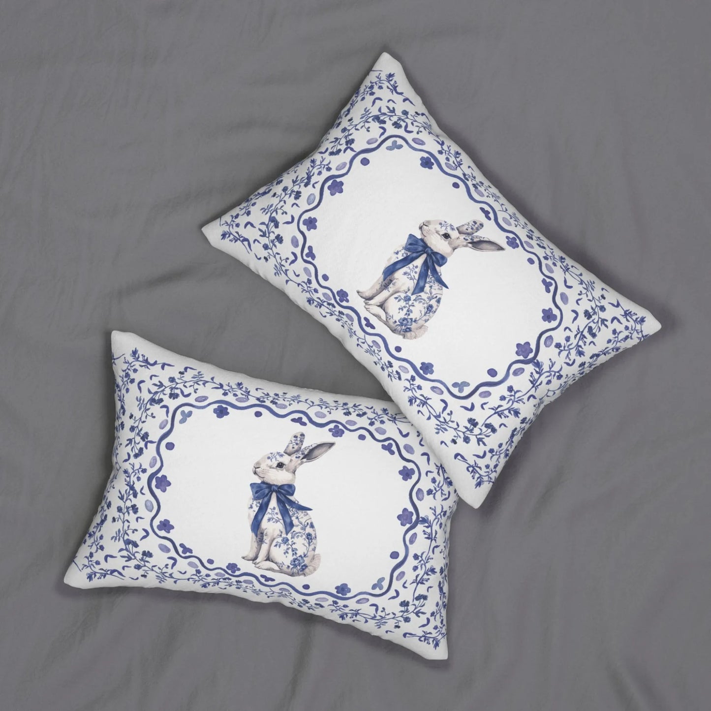 Two white lumbar pillows with a blue watercolor Chinoiserie rabbit and floral design on a gray background.