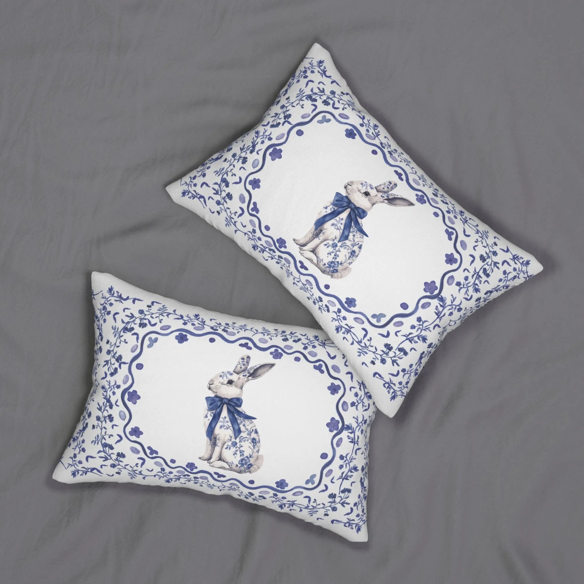 Two white lumbar pillows with a blue watercolor Chinoiserie rabbit and floral design on a gray background.