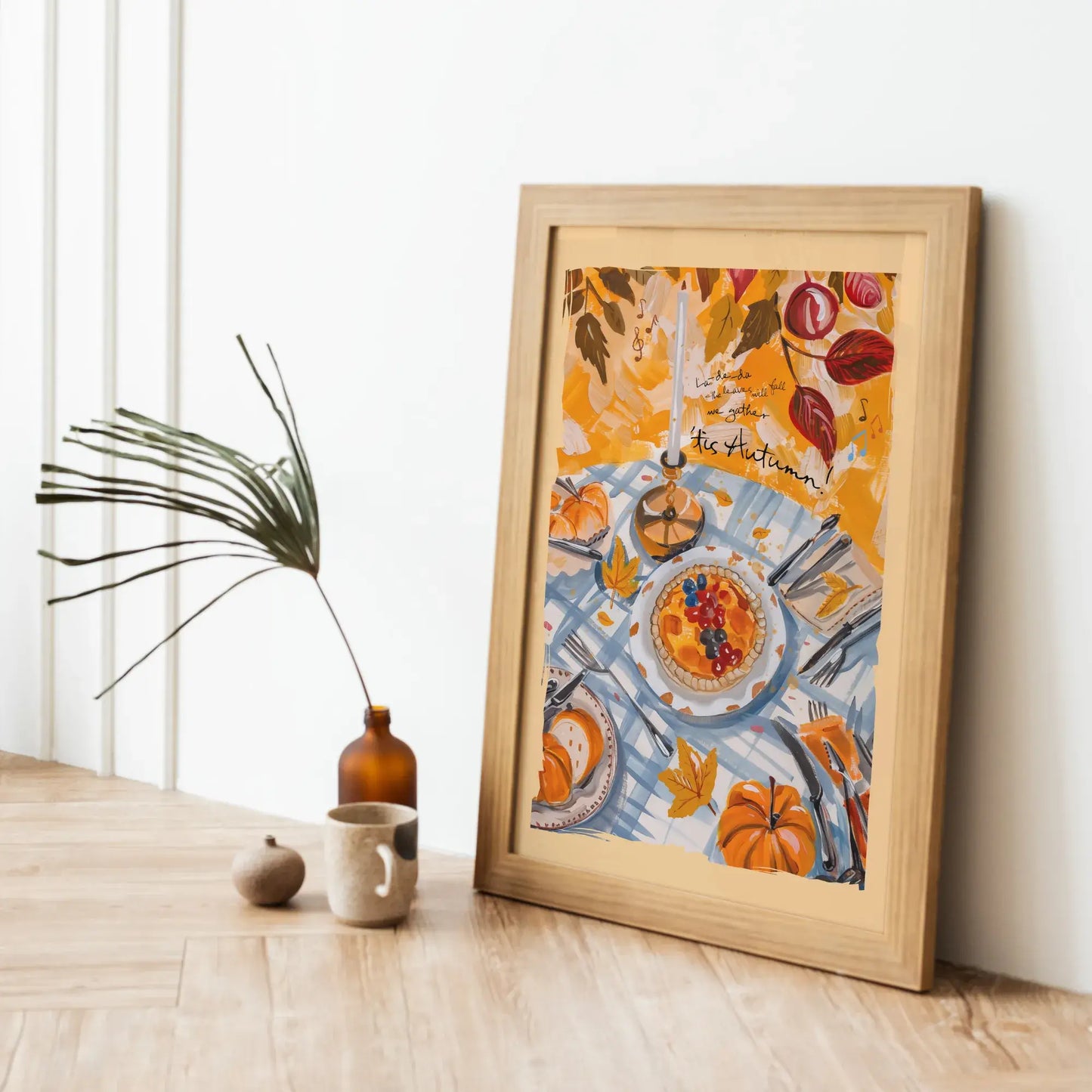 Framed fall wall art with pumpkins and harvest table scene, leaning on wood floor for cozy seasonal home decor