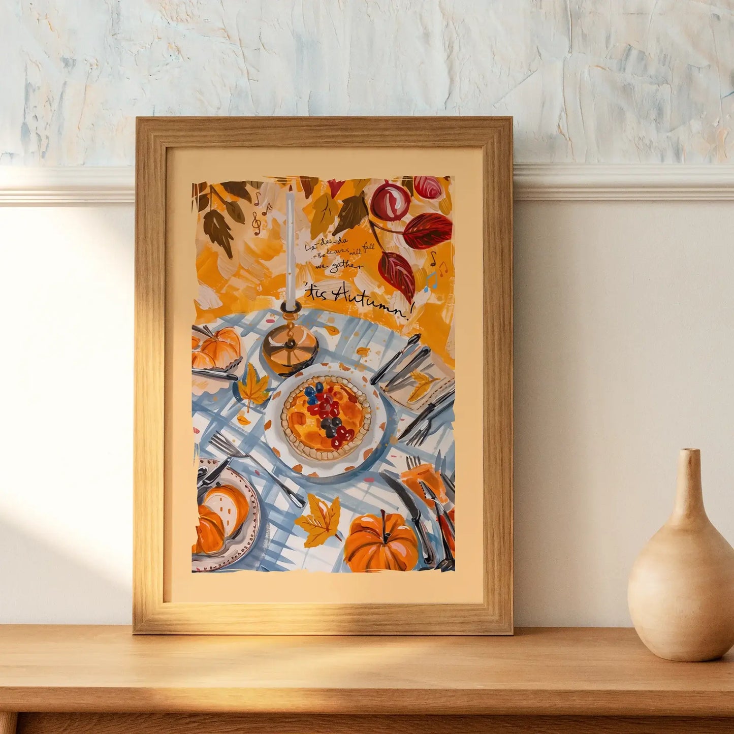 Framed fall wall art with pumpkins and autumn harvest table scene, styled on a wooden surface with ceramic vase