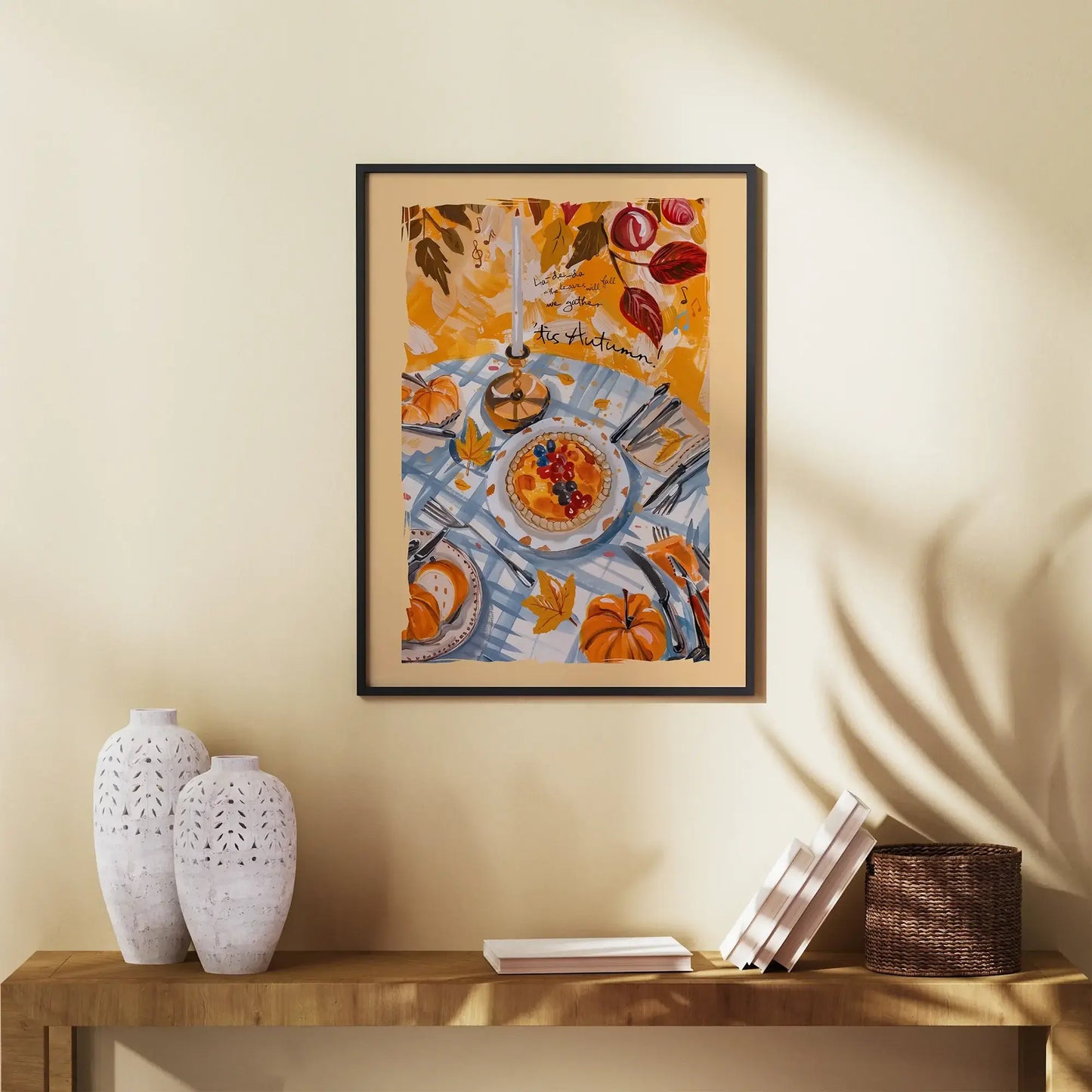 Framed fall wall art with pumpkins and autumn harvest table, styled above a wooden console with ceramic vases and books
