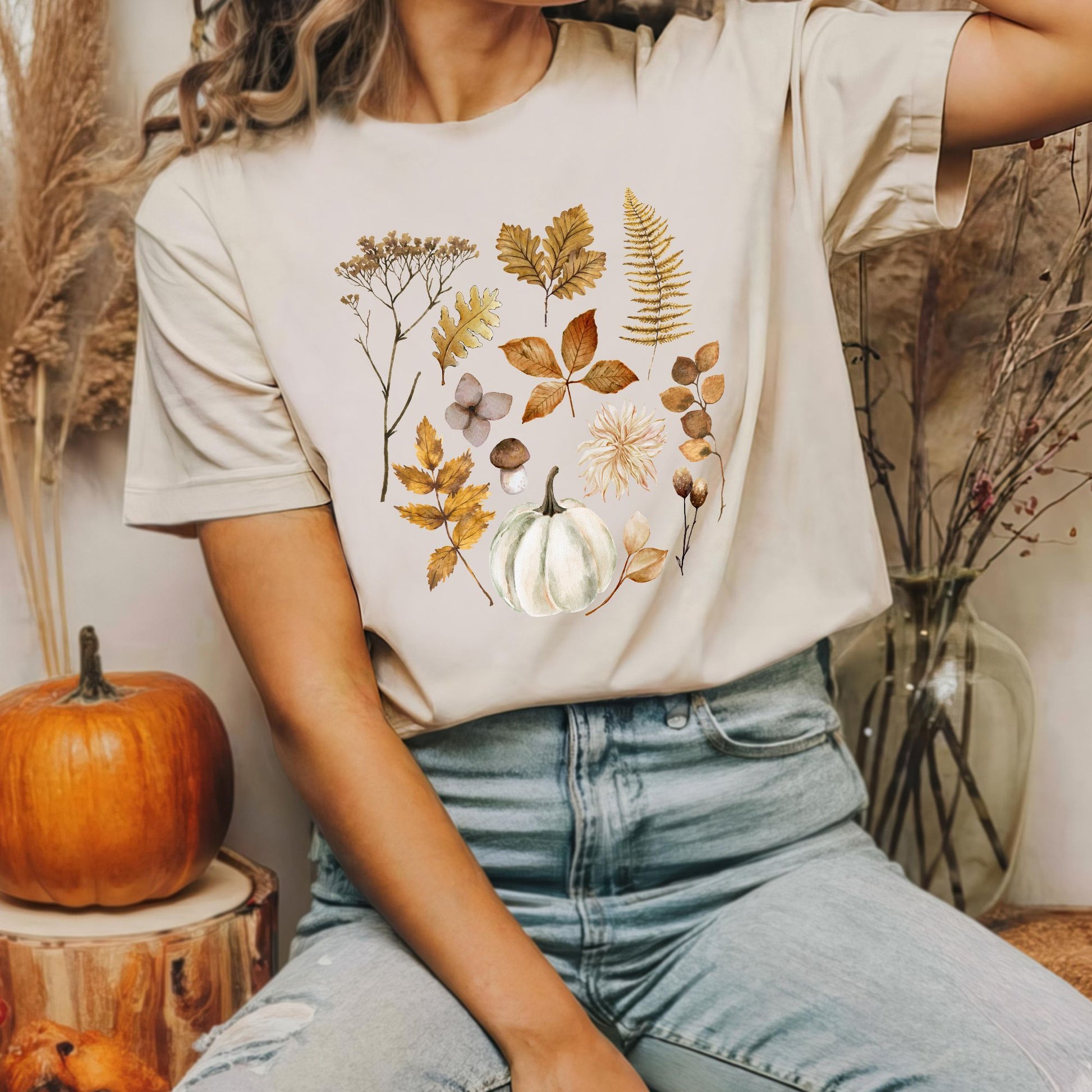 a girl in fall leave t shirt sitting next to a pumpkin