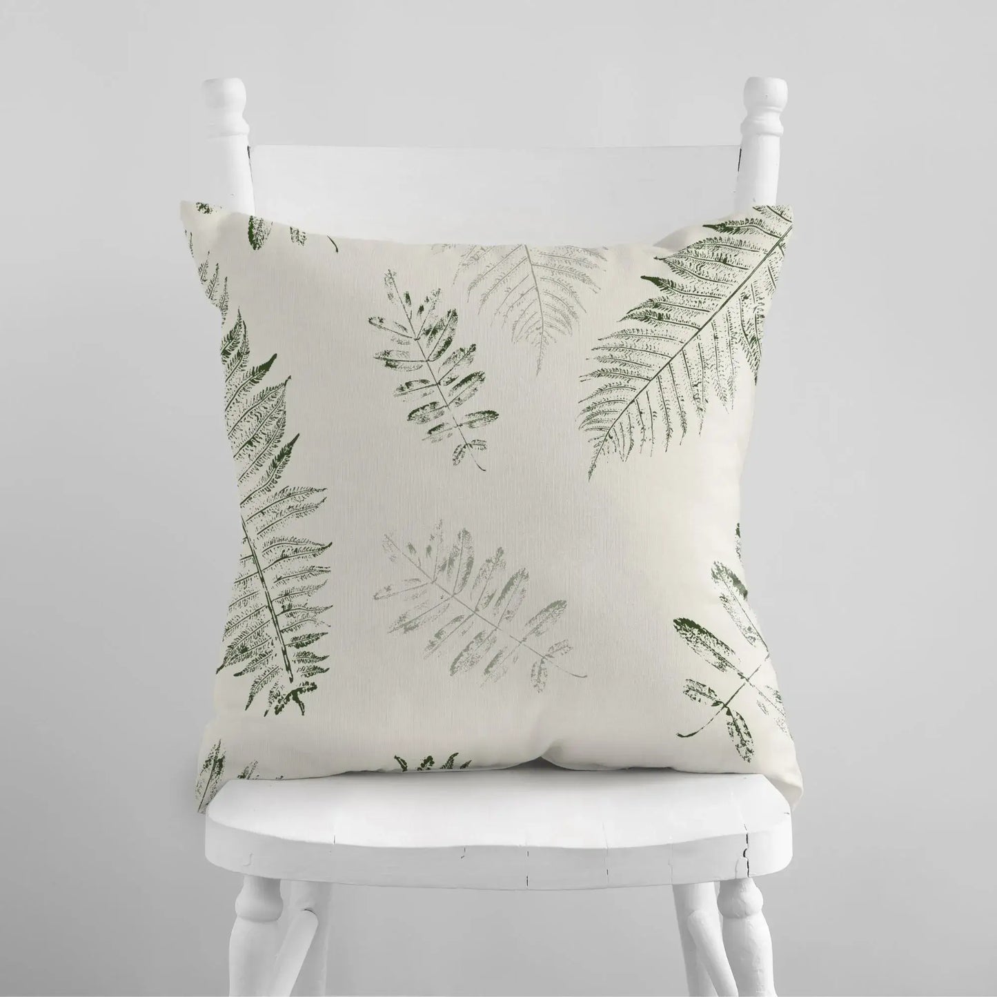 white chair with Green Leaves PILLOW from Blue Water Songs on it