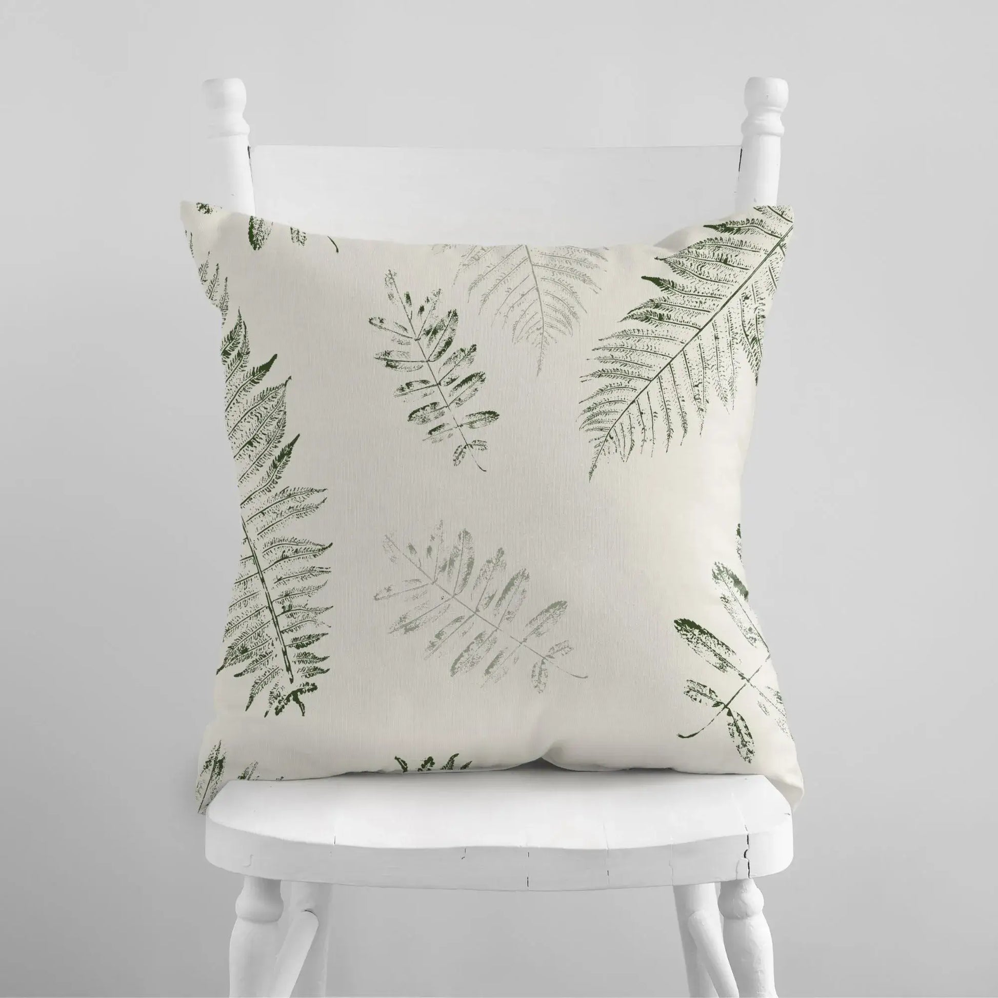 white chair with Green Leaves PILLOW from Blue Water Songs on it