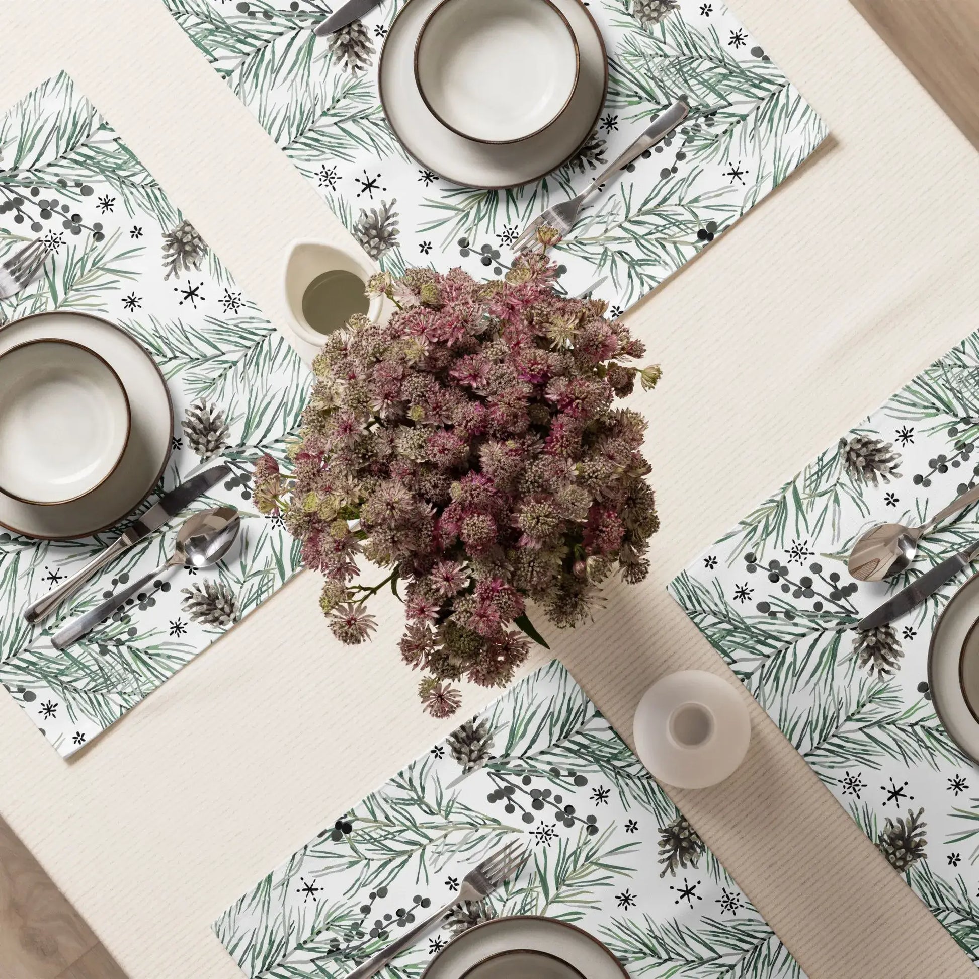 Green Pine and Berry Winter Botanical Placemats styled on a dining table with plates and a floral centerpiece.