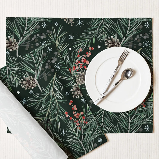 Green Pine and Berry Winter Botanical Placemats on a table with a white plate, fork, and spoon.