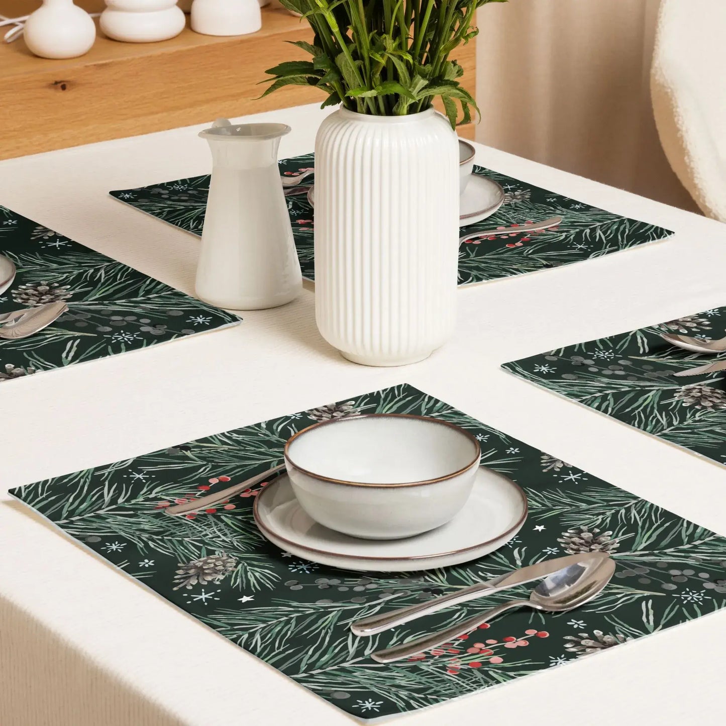 Green Pine and Berry Winter Botanical Placemats displayed on a dining table with bowls and utensils.