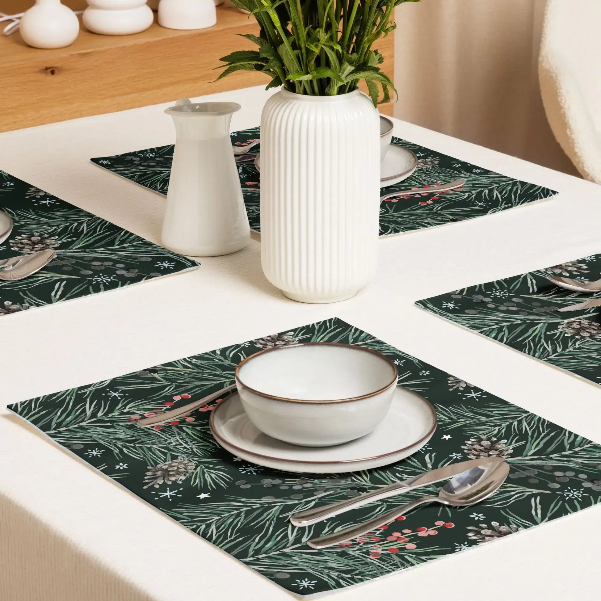 Green Pine and Berry Winter Botanical Placemats displayed on a dining table with bowls and utensils.
