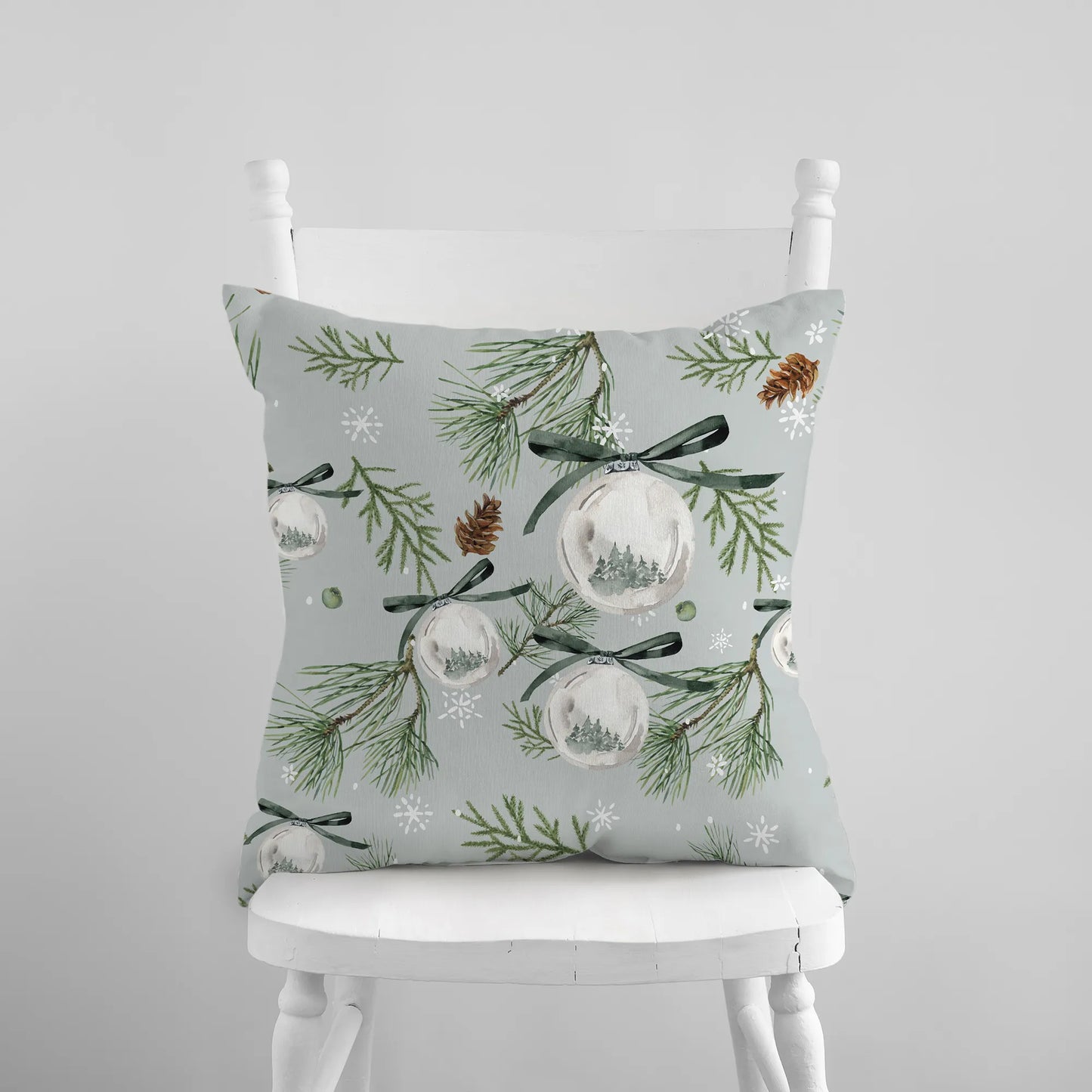 Watercolor green pine and ornament Christmas pillow on white chair – nature-inspired holiday decor