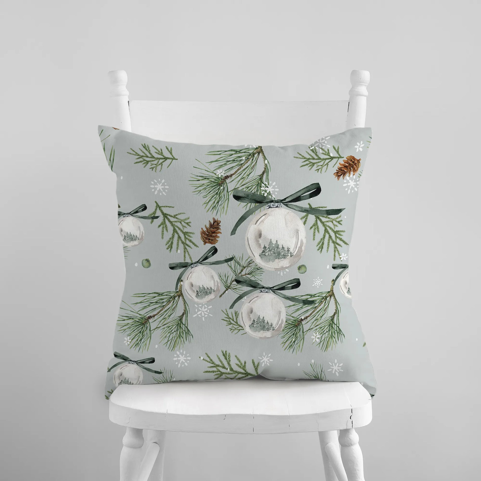 Watercolor green pine and ornament Christmas pillow on white chair – nature-inspired holiday decor